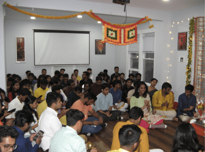 The main hall at the Illinois house during a festival evening, filled with students seated on the floor